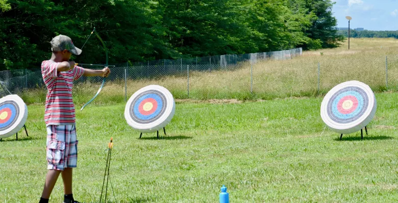 A kid in an archer's stance in front of a bullseye at Shelby Farms Park in Memphis