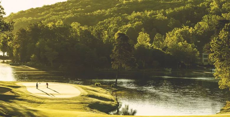 Golfing at Stonehenge Golf Course with a lake and mountains in the background.