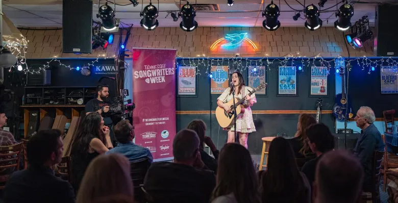 Woman playing on the stage of the famous Bluebird Cafe in Nashville, TN